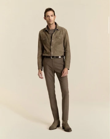 Model Pawel Binczak standing in a brown suede shirt, tailored trousers, and suede boots against a warm cream studio backdrop.