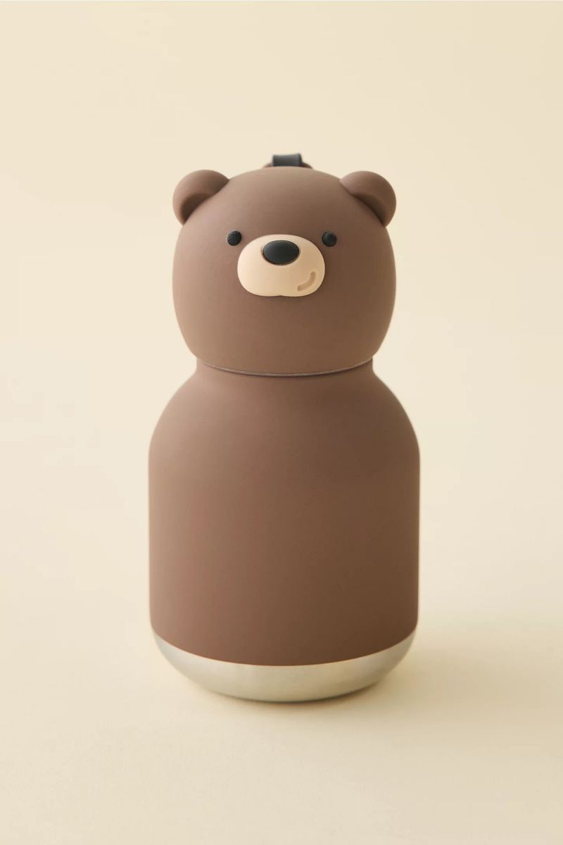A brown bear-shaped insulated water bottle by Asobu on a soft beige background, featuring a rounded head lid and silver metal base.