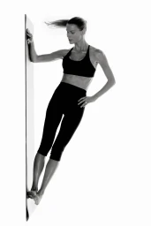 Alena Blohm poses dynamically in a black sports bra and cropped leggings against a white background for H&M Core Collection.