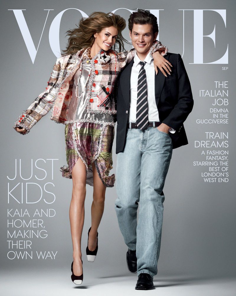 Kaia Gerber and Homer walk arm-in-arm against a grey backdrop for American Vogue magazine, featuring bold headlines and designer clothing.