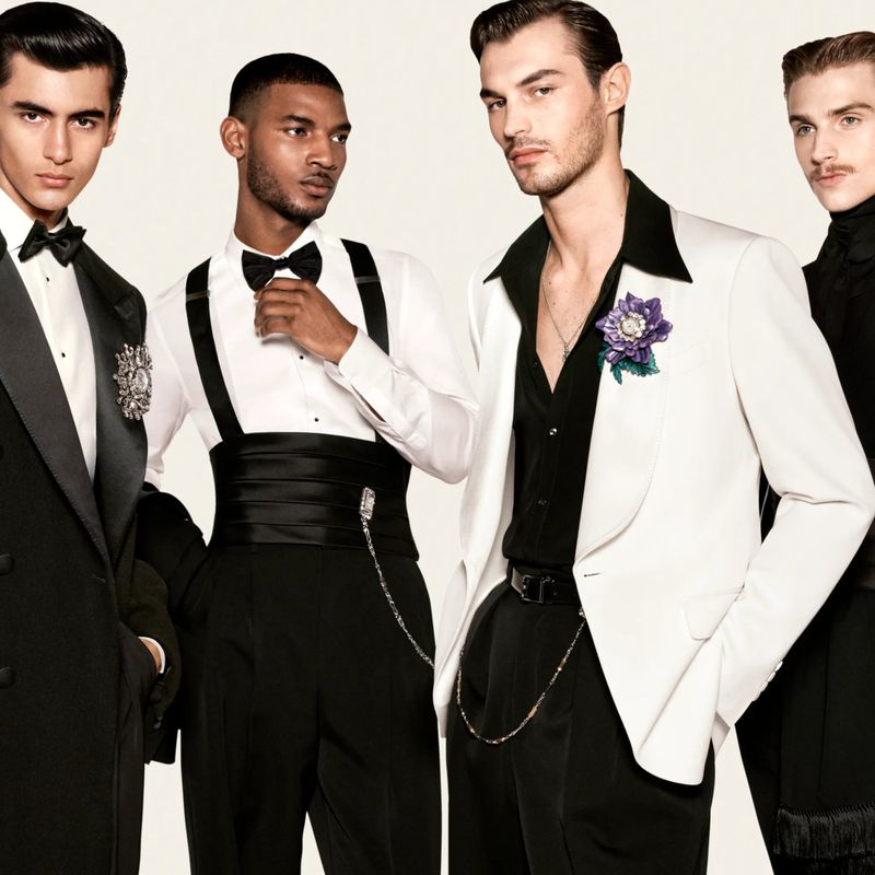 Four men in elegant black and white formal Dolce & Gabbana attire against a plain cream background.