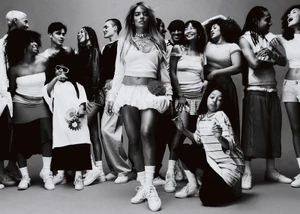 Karol G stands centered among a diverse group of models posing in white sneakers in a black and white studio portrait.