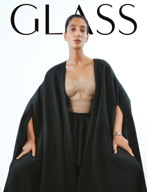 Magazine cover featuring a woman in a black cape and structured top against a white background with the word 'GLASS' at the top.
