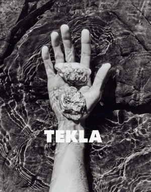 Black and white photo of an open hand holding two rough textured stones in shallow water with Tekla text overlay.