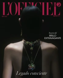 Red-haired model in a pinstriped black wrap dress with crossed arms on a white studio background for L'Officiel Chile.