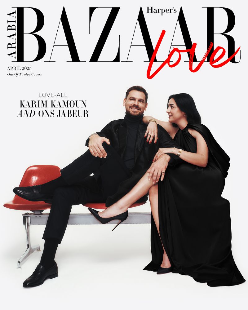 Harper's Bazaar Arabia cover featuring a man and woman in all-black attire, posed on a red bench against a stark white background.