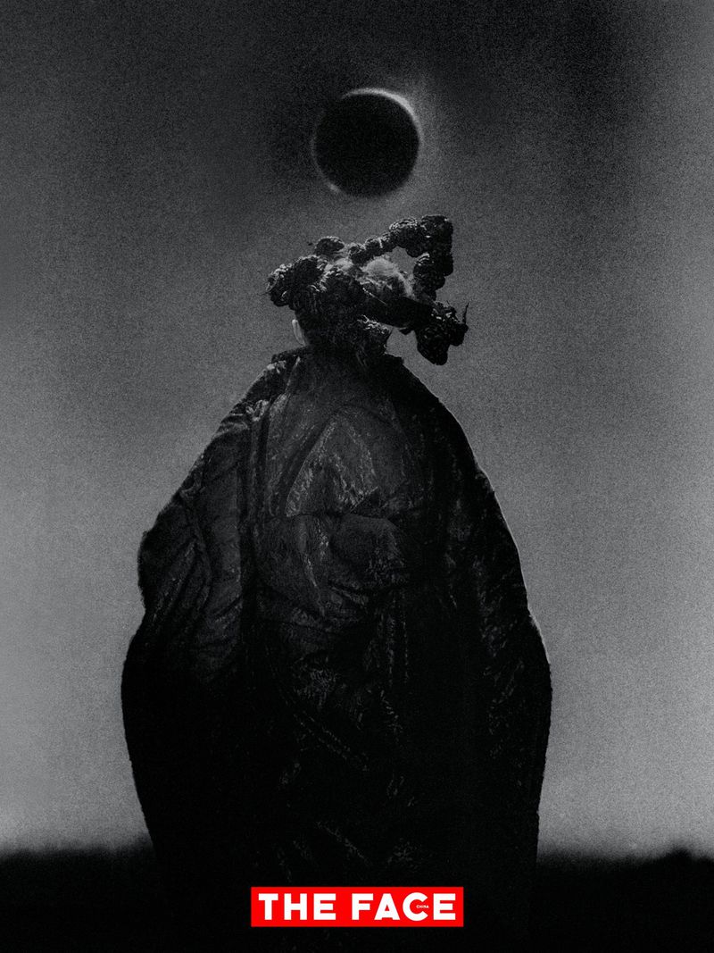 Monochrome fashion figure in a voluminous textured dark garment with a sculptural headpiece under a dark circular eclipse.