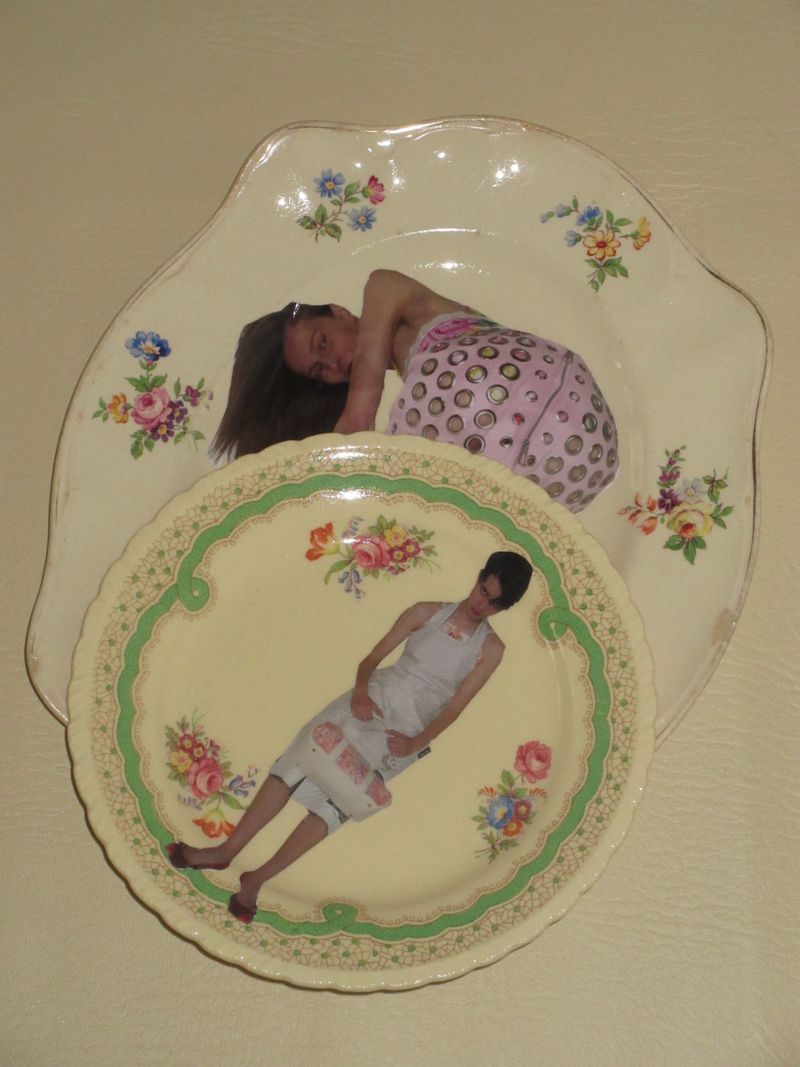 Two vintage floral ceramic plates displaying printed fashion editorial photographs of models against a plain cream background.