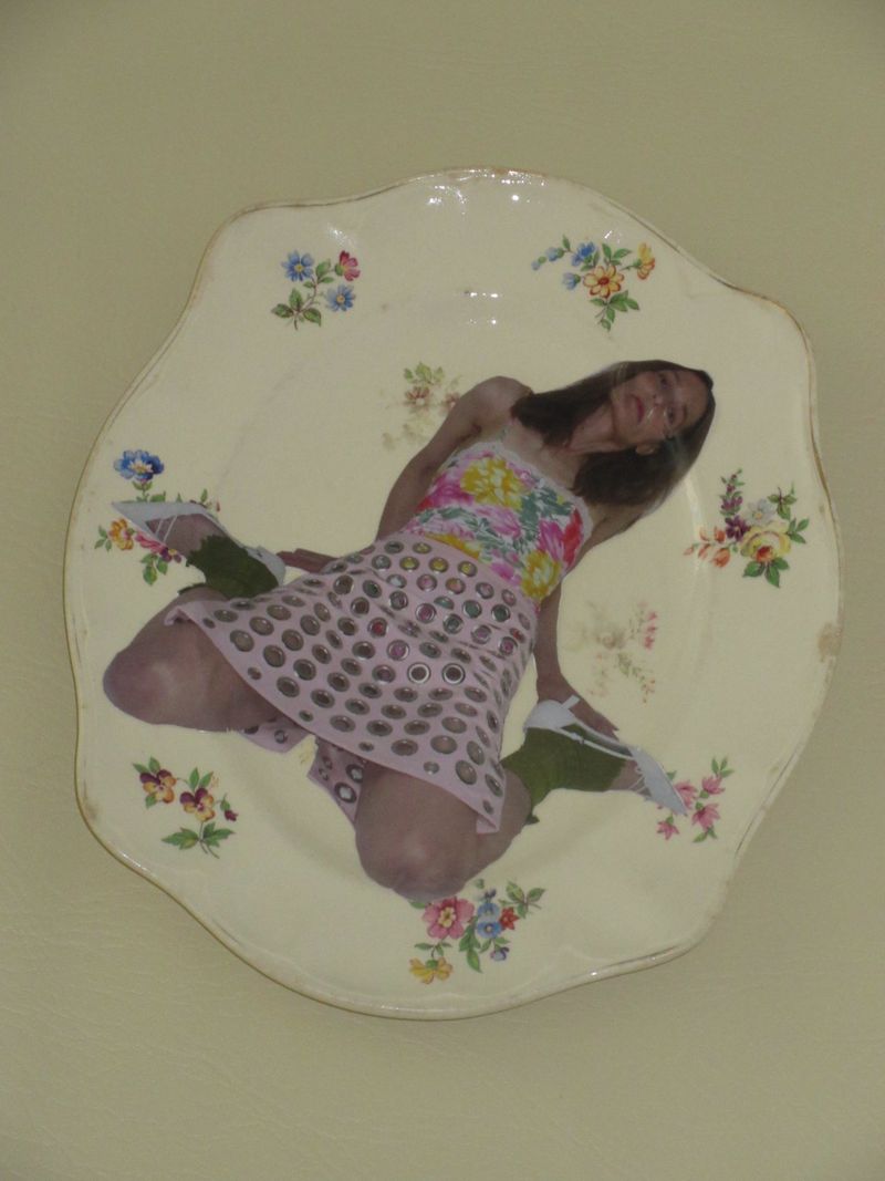 Vintage floral ceramic side plate with a collaged cutout of a woman in a floral top and pink skirt against a plain background.