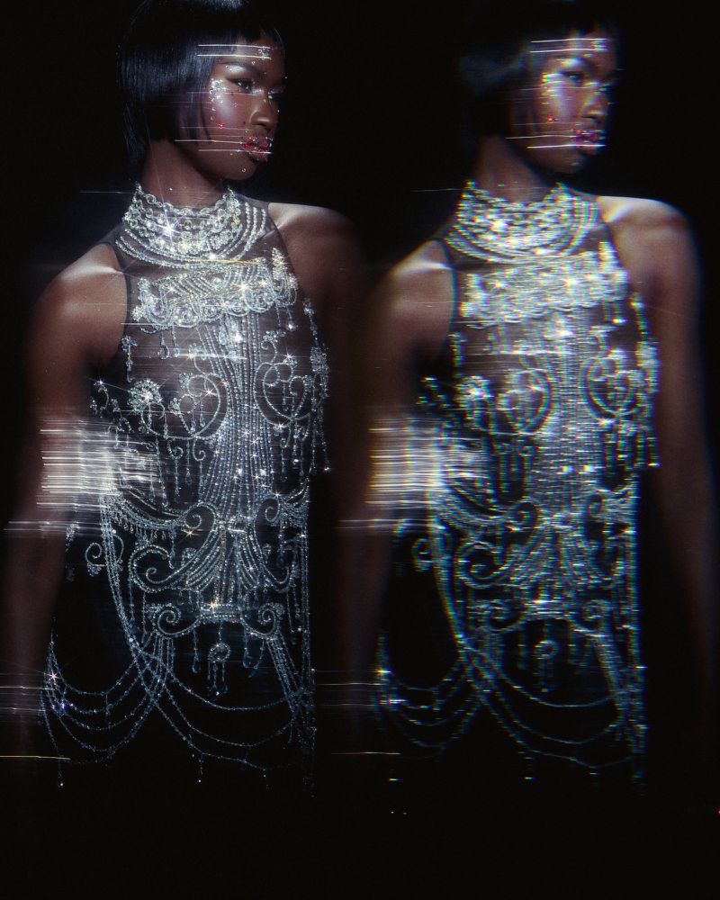 Nyarach Abouch Ayuel wears an intricate crystal-embellished halter dress against a black background with horizontal streak effects.