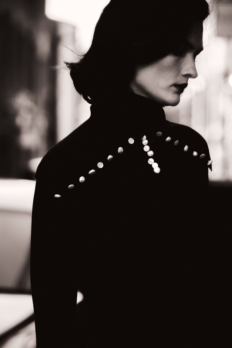 Monochrome profile portrait of model Lara Mullen wearing an embellished high-neck black top with stud detailing.