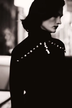 Monochrome profile portrait of model Lara Mullen wearing an embellished high-neck black top with stud detailing.