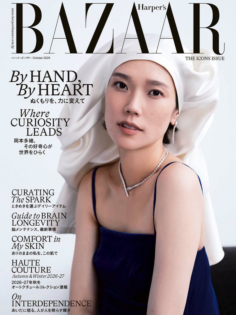 A woman with short dark hair wears a white silk head wrap and a dark blue velvet camisole on a Harper's Bazaar magazine cover.
