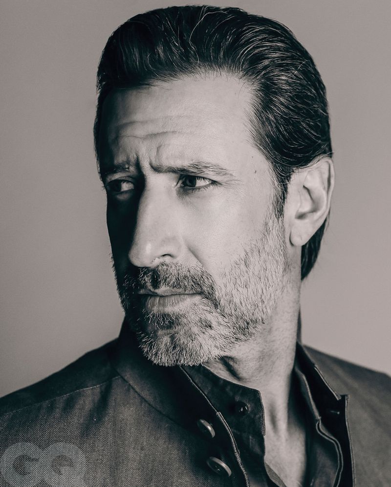 Monochrome close-up portrait of actor José María Yazpik looking to the side wearing a dark mandarin collar jacket.