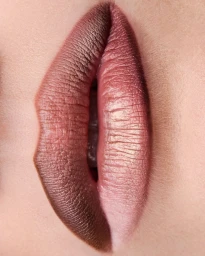 Extreme macro close-up of slightly parted lips wearing a gradient of shimmering mauve and metallic rose-gold lipstick.