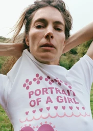 Model Jessica Miller pulling off a white t-shirt with pink graphic lettering in an outdoor natural environment.