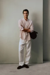 Francisco Henriques posing in a blush linen shirt and white trousers for Massimo Dutti lookbook against a neutral studio backdrop.