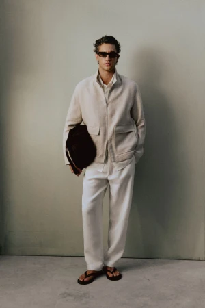 Francisco Henriques wearing a beige zip jacket, off-white trousers, sunglasses, and sandals for Massimo Dutti lookbook.