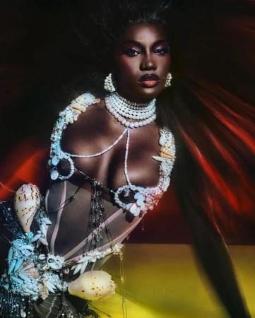Dark-skinned woman with dramatic makeup, wearing a seashell-embellished bodice and pearl jewelry against a dark, dynamic background.