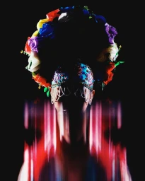 Portrait of a figure wearing an ornate floral and beaded headdress with vertical motion blur streaks against a black background.