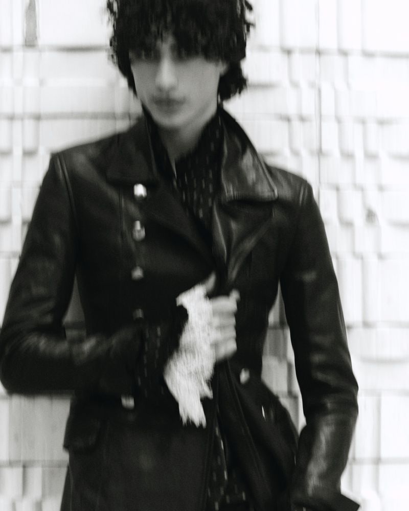 Model Yoesry Detre wearing a black leather jacket with a white lace cuff in a black and white editorial portrait.