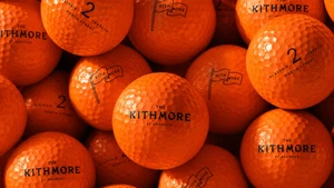 Close-up of bright orange golf balls printed with black branding for The Kithmore St Andrews.