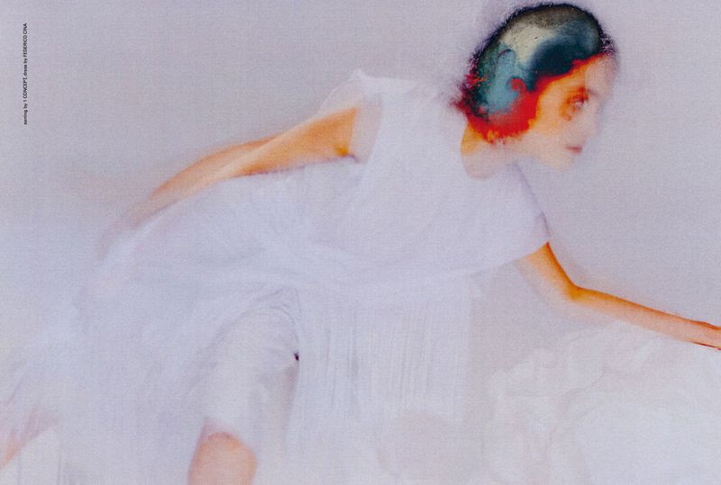 Woman in a white dress captured with motion blur, creating an artistic effect in a minimalist setting with soft, diffused lighting.