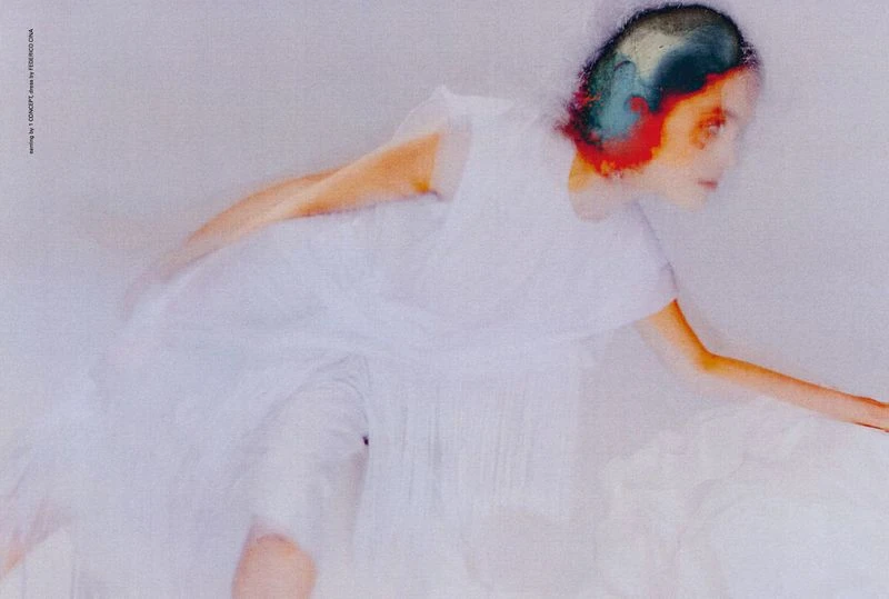 Woman in a white dress captured with motion blur, creating an artistic effect in a minimalist setting with soft, diffused lighting.