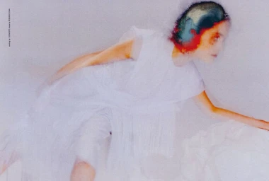 Model in white dress captured in motion blur with colourful hair against a neutral background