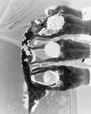 Monochromatic fashion shot features woman in ornate gown, assisted by four men. Negative effect and studio lighting create a striking visual.
