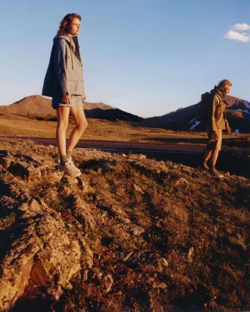 Amelie Sante and Peter Dupont wearing technical outerwear on a rocky mountain slope during golden hour for Hardpack Magazine.
