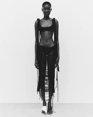 Model Aluk Malual posing in black cutout apparel against a white background for 10 Magazine Deutsch editorial