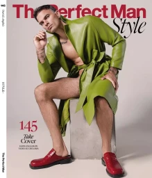 Male model in an open lime green leather coat and red slip-on mules seated on a concrete block against a studio background.