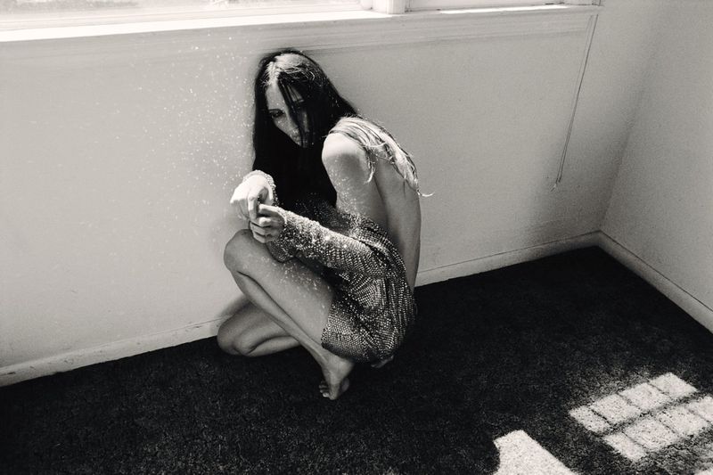 Model Waleska Gorczevski crouches in an interior room corner wearing a sequined mini dress in high-contrast black and white.