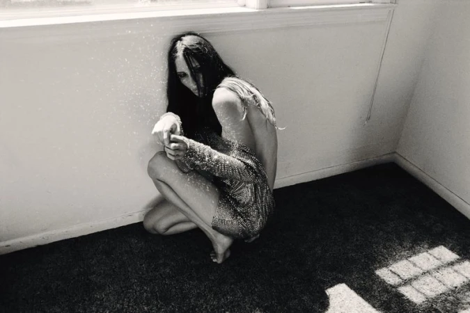 Model Waleska Gorczevski crouches in an interior room corner wearing a sequined mini dress in high-contrast black and white.