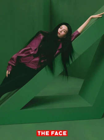 Model Sui He poses across a green geometric set piece wearing a magenta jacket and black trousers for The Face China.