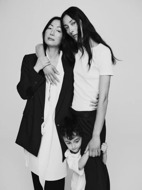 A family portrait in black and white featuring an adult woman with an older woman and a child. Shot in a photo studio on a white backdrop.