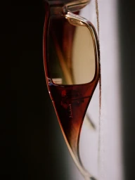 Close-up profile of brown amber acetate Balmain sunglasses with tinted lenses against a muted background.