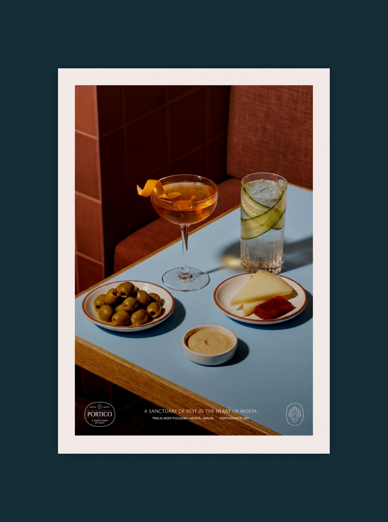 Cocktails in glassware served alongside olives, cheese, and dip on a light blue table for Portico brand identity.
