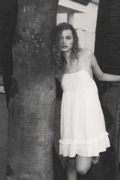Model in a white dress leaning against palm trees for the H and M Malaga lookbook