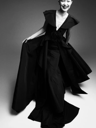 Model Gigi Hadid smiling in an expansive black evening gown against a studio backdrop for Vogue France.