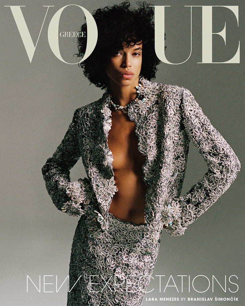 Model Lara Menezes on Vogue Greece cover wearing a textured grey floral lace blazer and matching skirt against a neutral studio backdrop