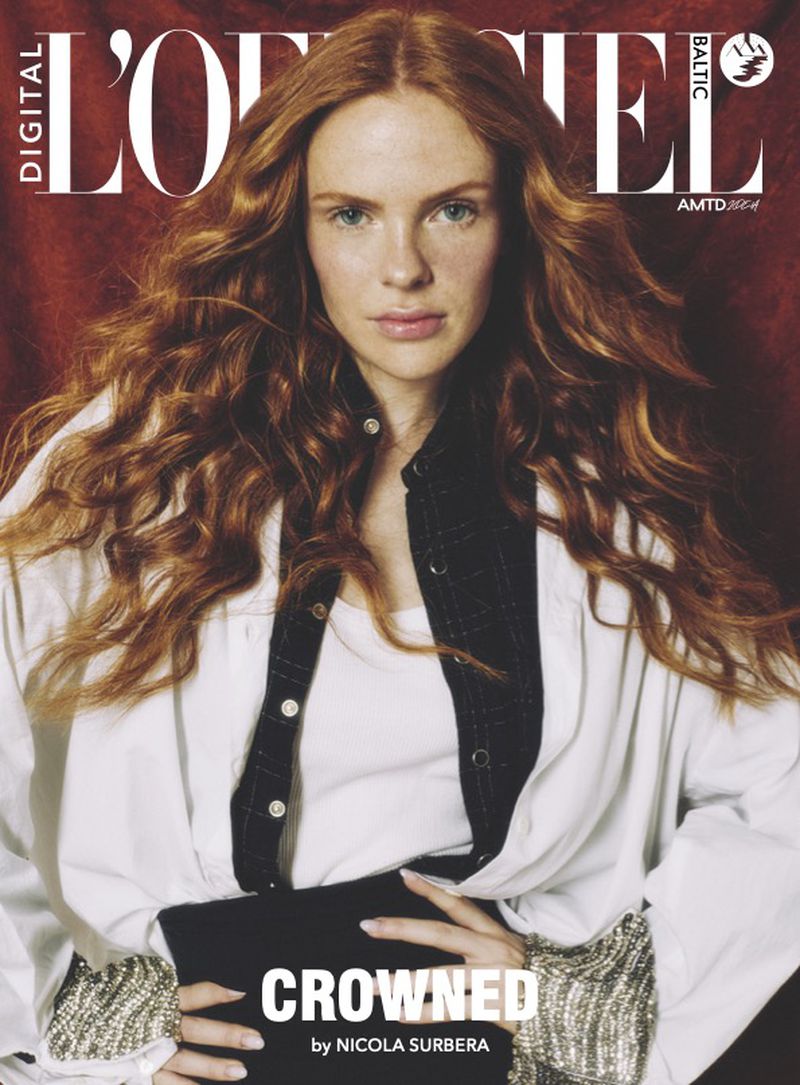 Fashion magazine cover featuring a red-haired model in a white shirt and black skirt against a dark red background, showcasing a high-fashion editorial style.