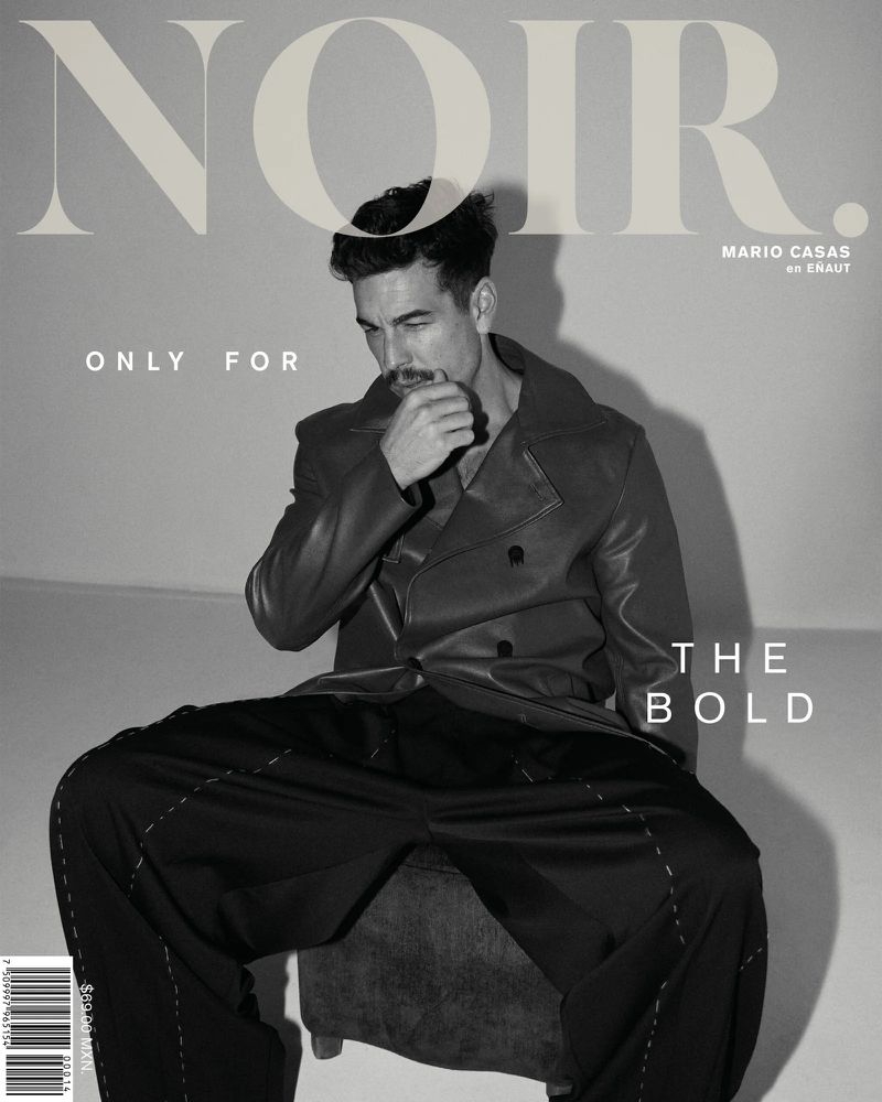 Black-and-white magazine cover shot of a man in a leather jacket and black pants, seated against a plain background, with overlaid text.