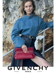 Eva Herzigova in a blue leather top holding a red leather clutch against a rocky cliff in a Givenchy campaign by Juergen Teller.