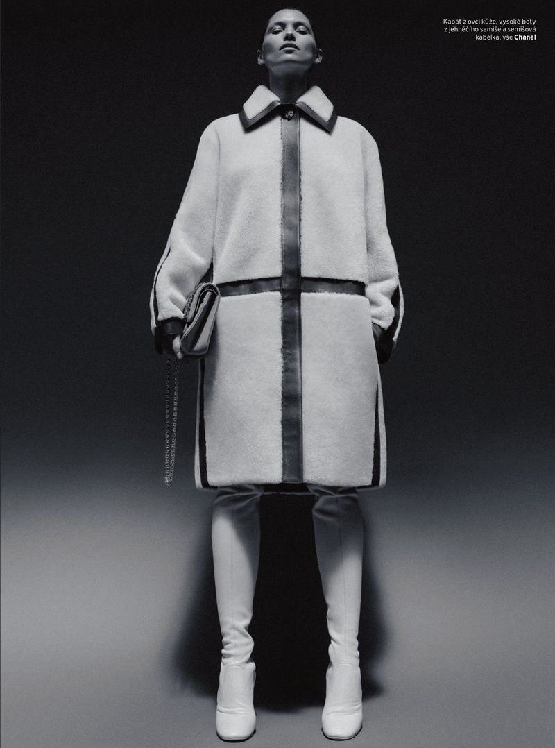 Model Hana Jirickova posing in a white shearling coat with dark leather trim and matching white boots against a dark gradient backdrop.
