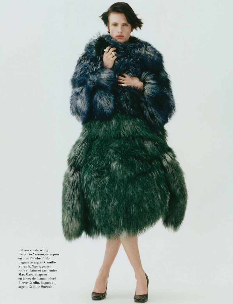 Model Charlie Jones posing in an oversized two-tone shearling coat and black high heels against a white seamless background.