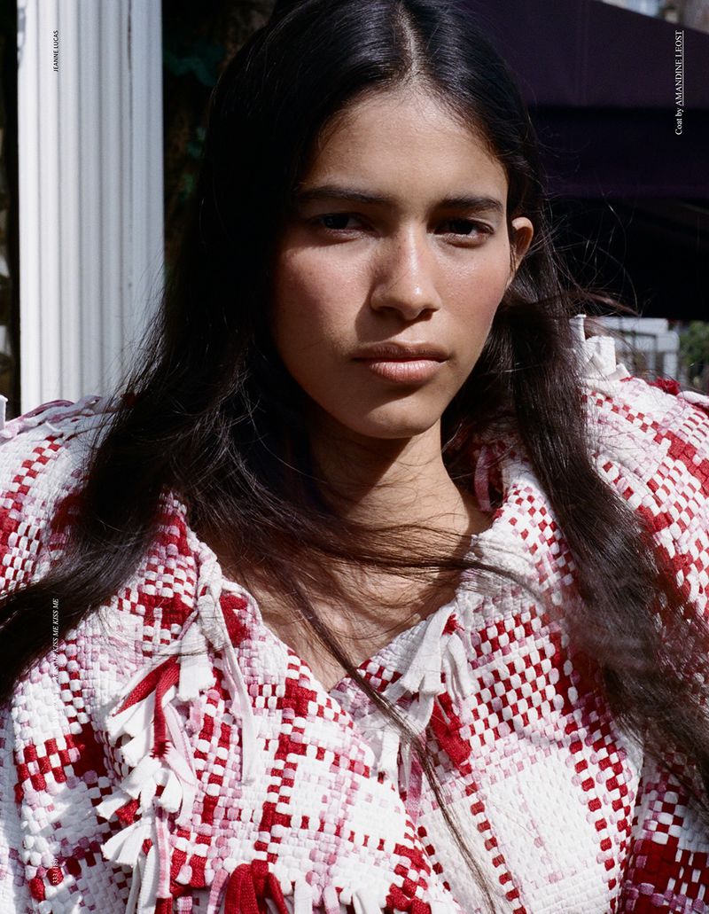 Model Liseth Sairys wearing a red and white textured woven fringed jacket in direct outdoor sunlight.