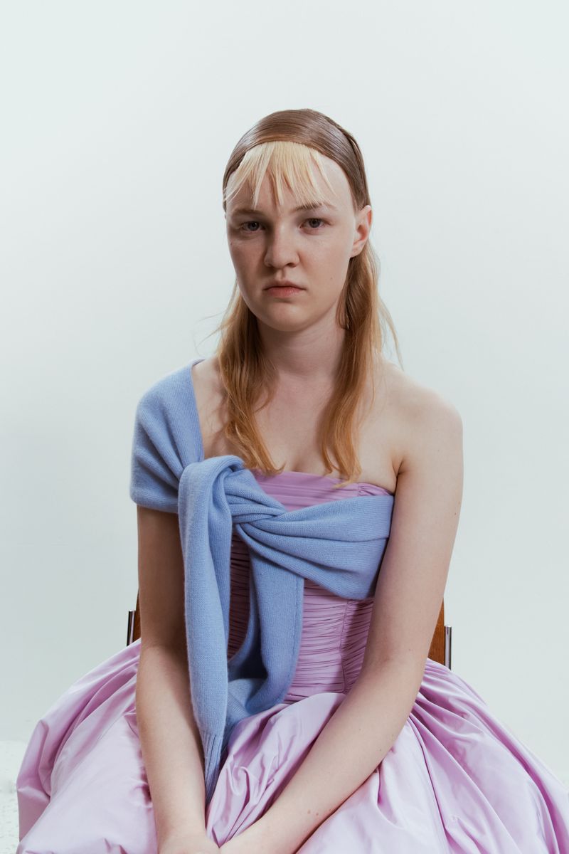 Model wearing a lilac strapless dress with a powder blue knit tied across her chest against a white background.