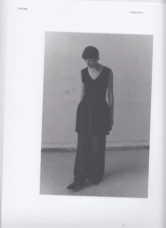 Model Sara Blomqvist wearing a black sleeveless knit tunic and wide-leg trousers in a monochrome studio portrait.